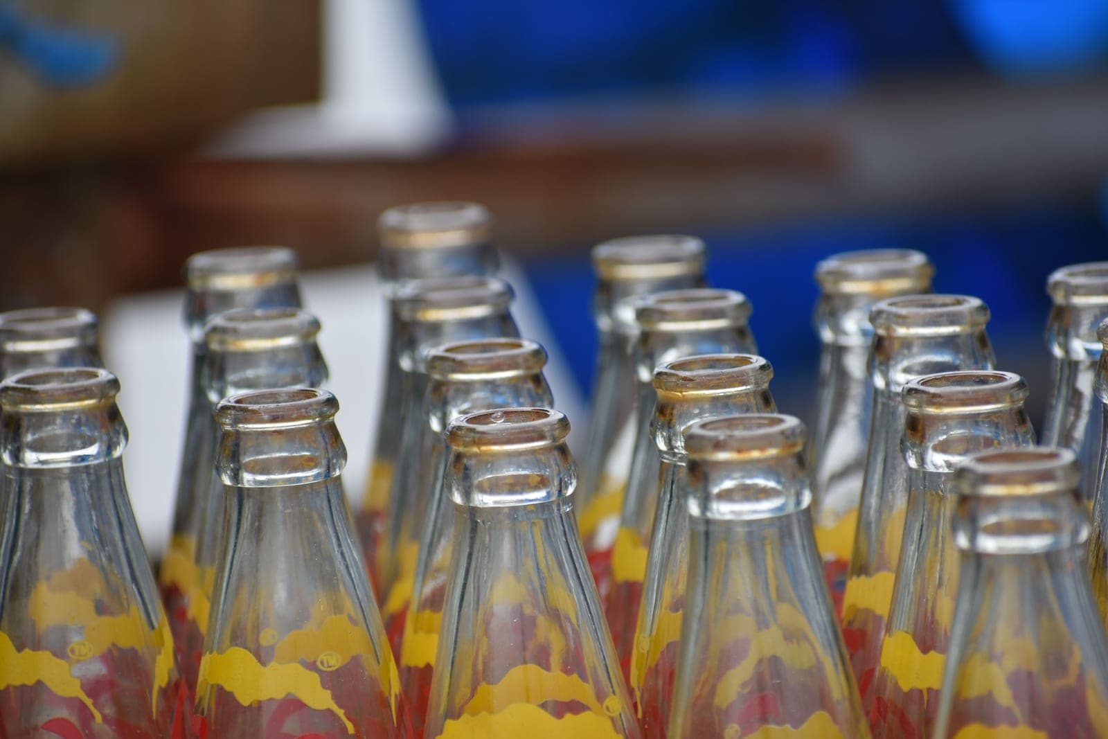 A row of swing-top glass bottles standing on a pale surface in bright daylight